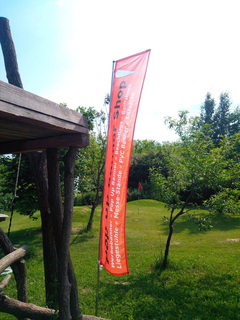 Beachflag Edge als Werbebanner in einem Garten
