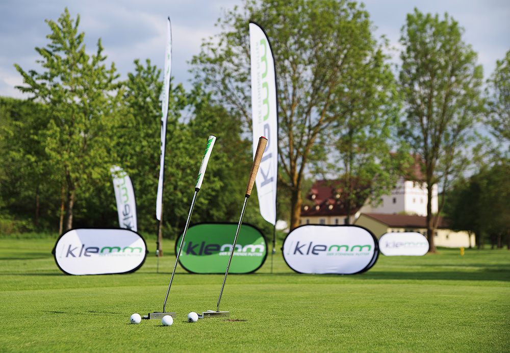 Auf dem Bild sieht man Pop Up Banner und Beachflags auf einem Golfplatz. Bäume und kurz gemähter Rasen sind zu sehen.